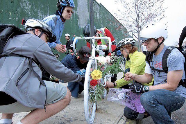 Cyclists decorate a memorial to a killed bike rider.